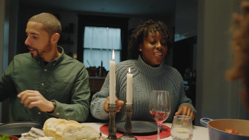 Girl serving sauce over a dish of spaghetti on the dinning table with her family