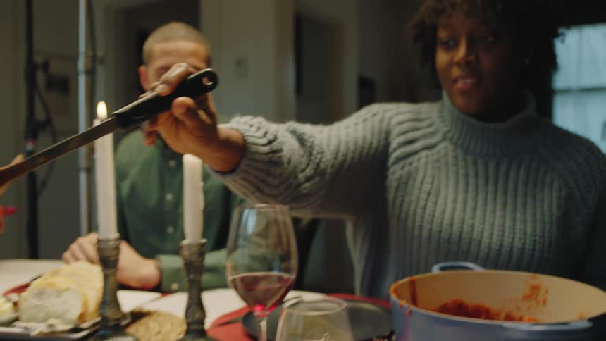 A woman smiles as she serves dinner at the table
