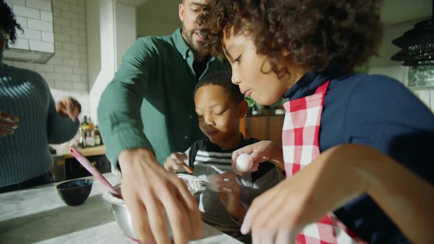A family is mixing ingredients in the kitchen together