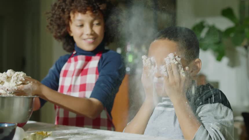 Boy playing with flour while cooking with his family at home