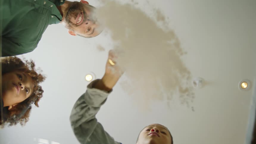 A family watch as the boy pours flower on the glass