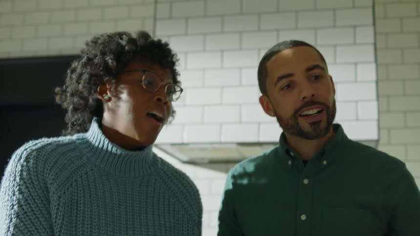 A man and a woman are standing inside talking and smiling