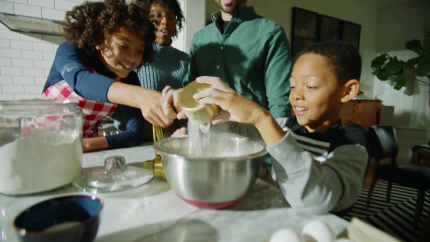 A family is having fun preparing a recipe in the kitchen in the evening