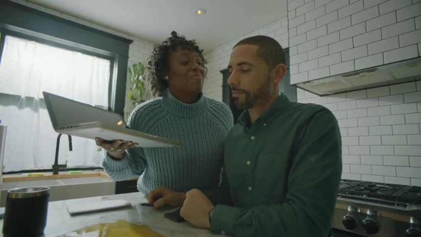 A woman is standing with her laptop and a man has spilled orange juice