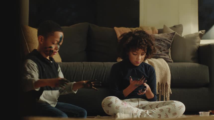 A boy and his sister play with black finger paints