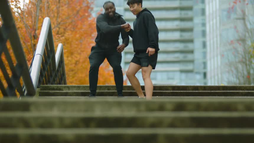 Two men rush down steps in a public park in a large city on a fall season day