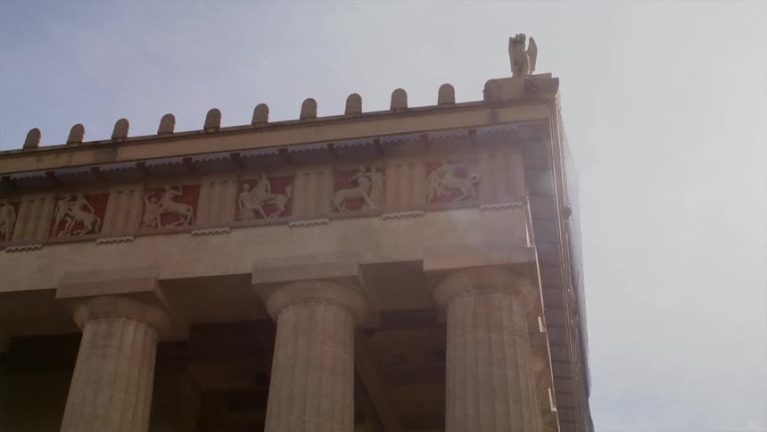 A large building is surrounded by stone pillars