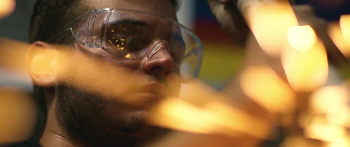 Mechanic cutting metal with a power tool inside an auto repair shop