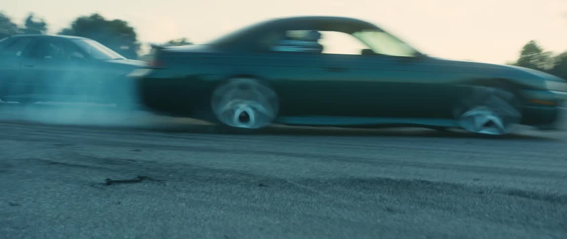 Two cars drifting on a curve in the race track at sunset