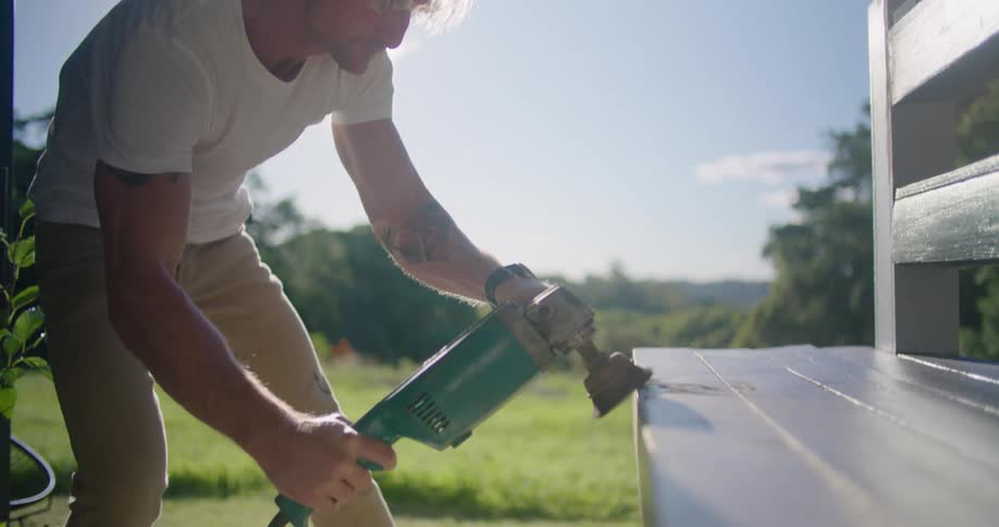 A man is sanding a bench with a machine