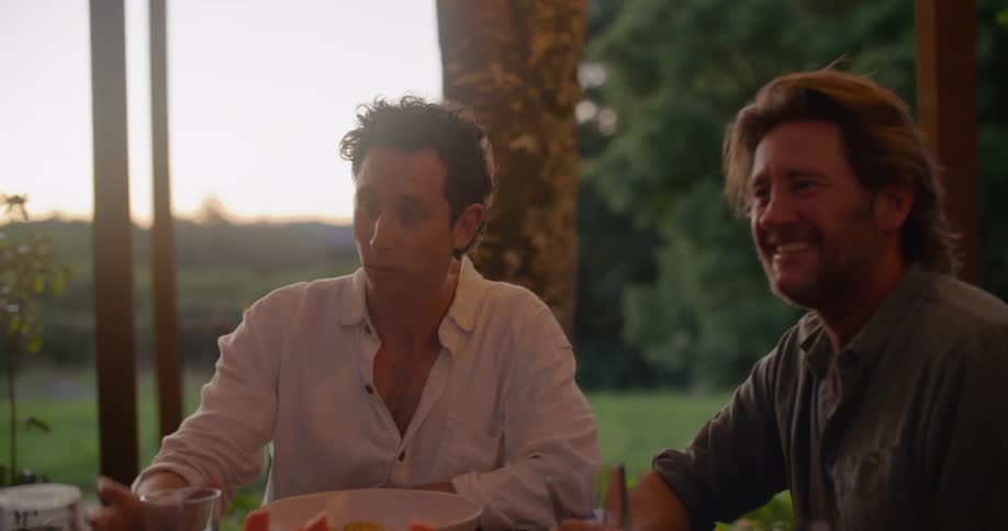 Two men talk and eat outside
