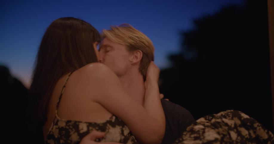 Man holds woman in his arms and kisses her as they spin around