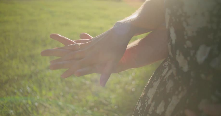 A man stands behind a woman with his one hand resting on her stomach as they put their hands together and entwine fingers to hold hands