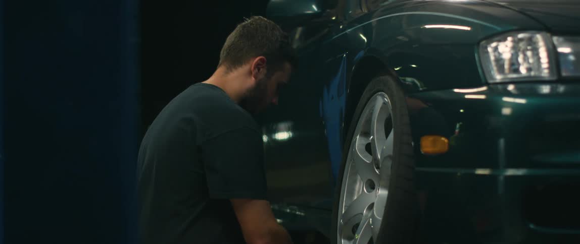 Young mechanic removes the tire of a car on an auto shop