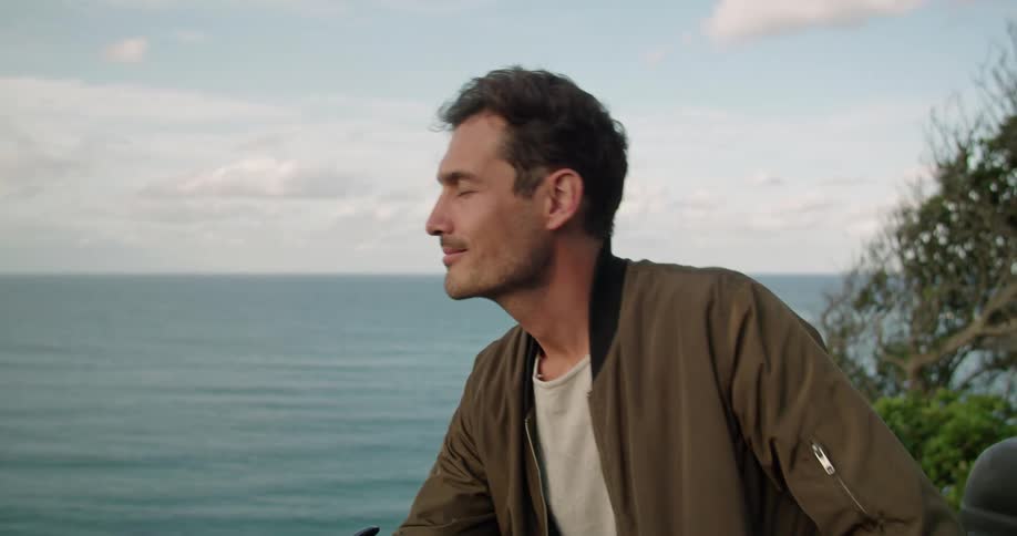 A man is standing outside looking at the ocean