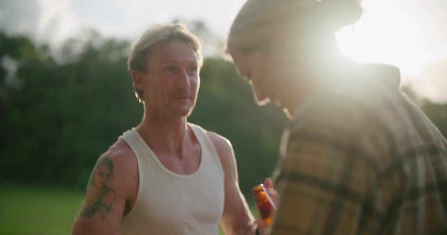 A couple laughing and having a good time while drinking beer outdoors at evening