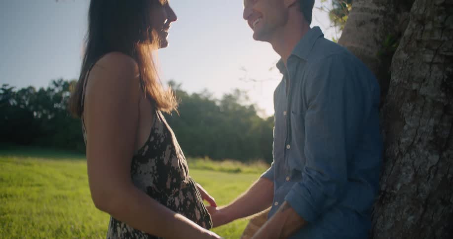 A couple hold hands by the large tree