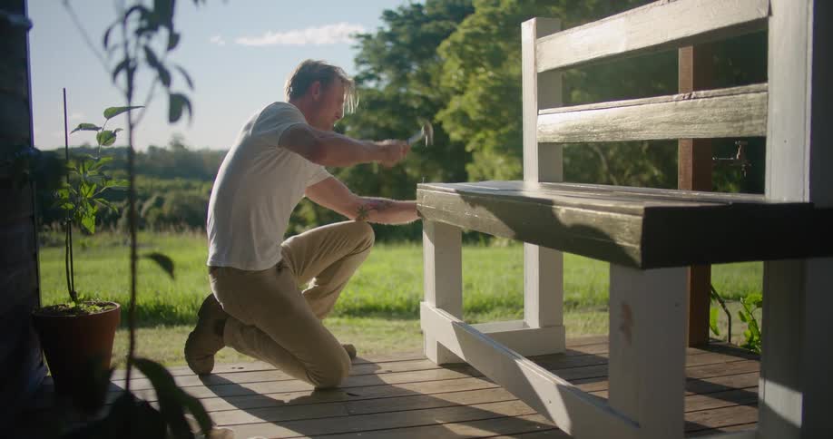 Person putting nail in bench