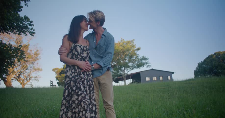 A couple kiss while standing on the green grass