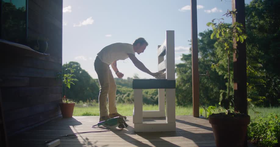 Young man cleaning a bench in the porch at home in the morning