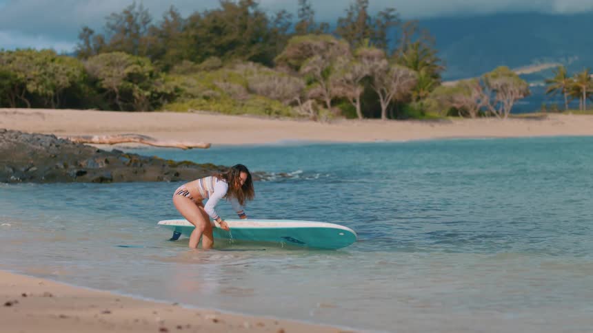 A woman picking up a surfboard outdoors