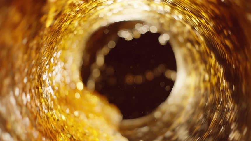 Yellow liquid is spinning in a circle inside glass