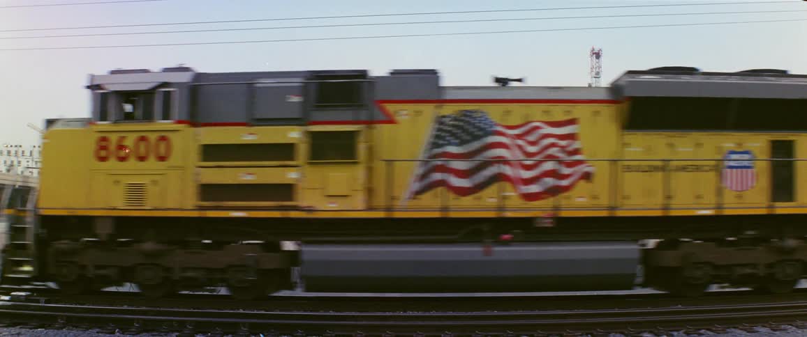 A train moves by with buildings in the distance