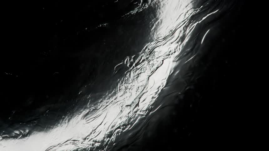 Light reflecting on water flowing on ice on a black background