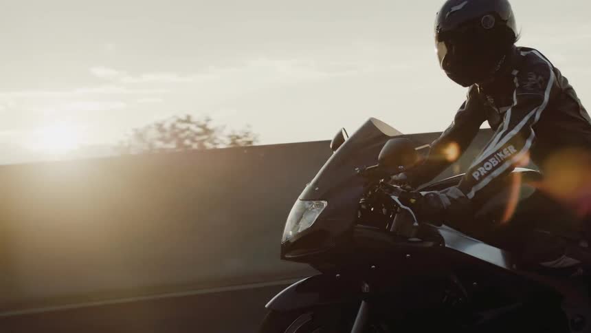 A person is riding their motorcycle at sunset