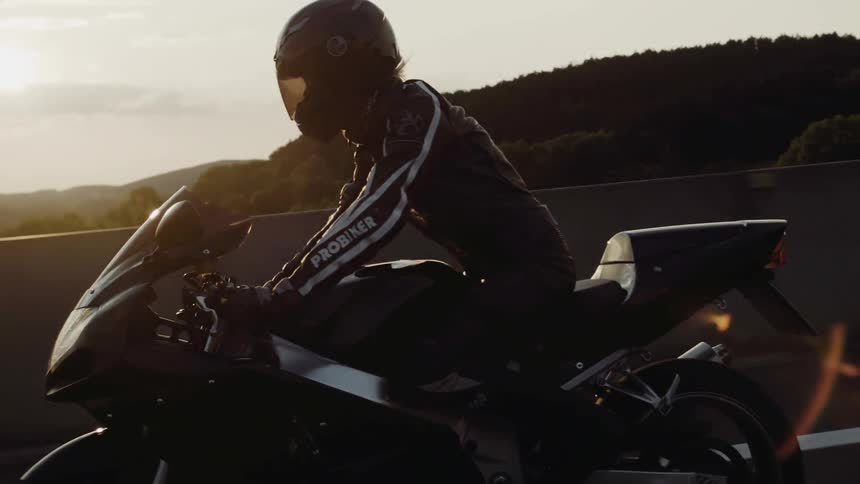 A person wears a helmet and suit while riding a motorcycle