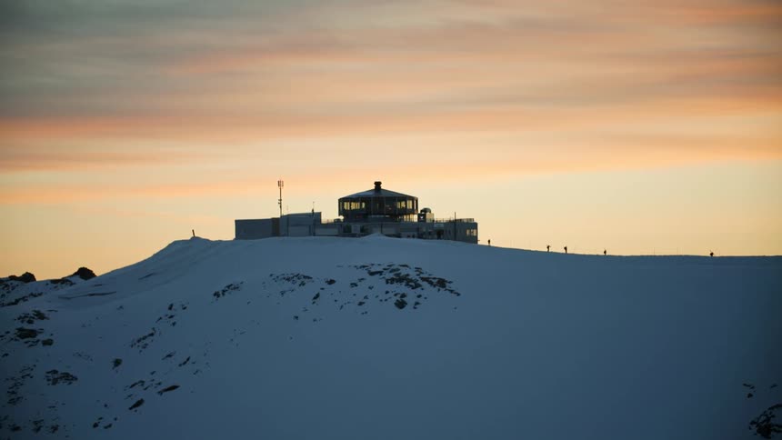 A group of people leave a ski resort on top of a snow covered hill