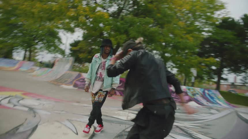 Two young dancers breakdancing on a skate park filled with graffiti