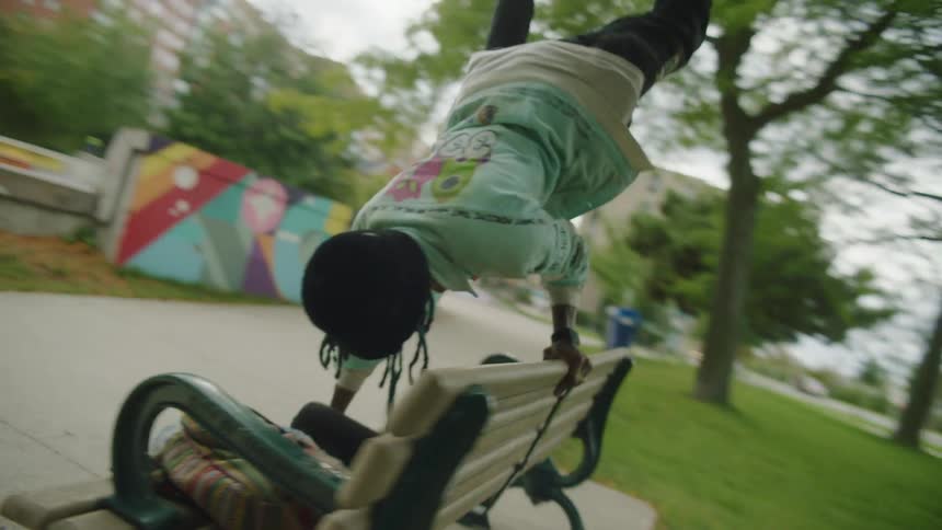 A man is doing a handstand on a park bench