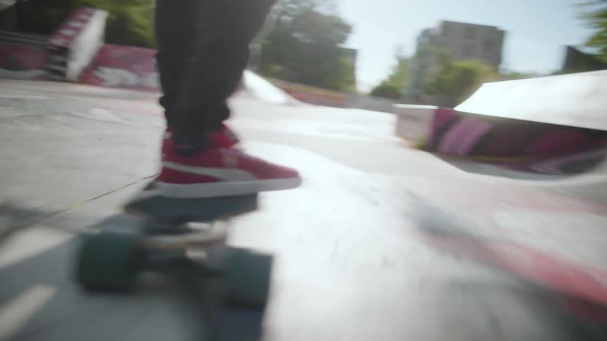 Skateboarder rides skateboard through skate park decorated with graffiti art