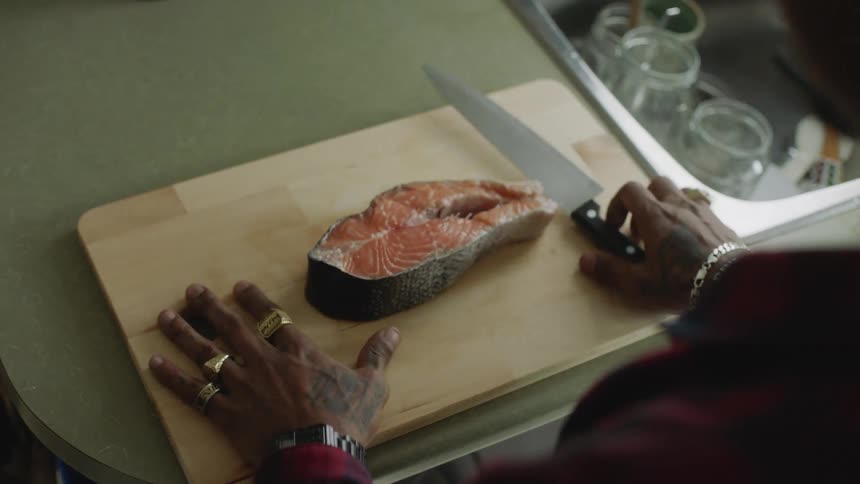A man begins to cut a piece of fish then stops