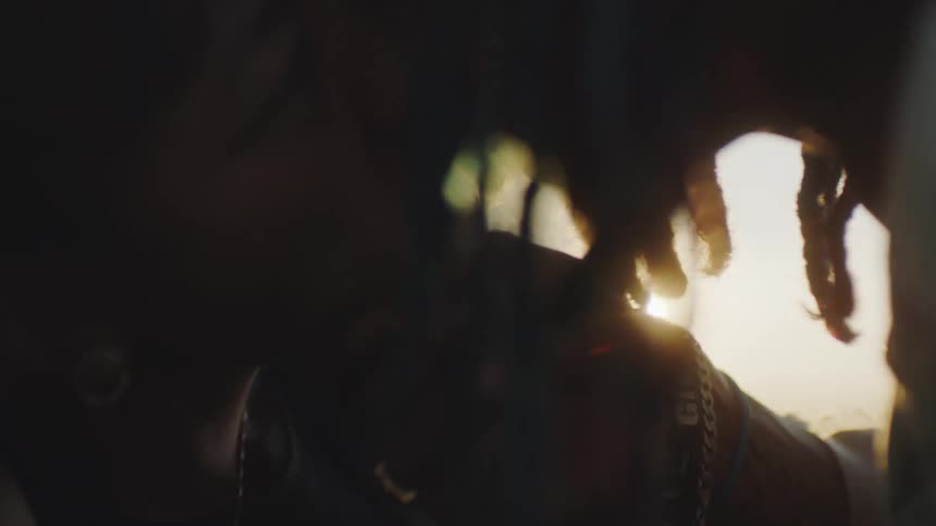 A man and a woman are kissing as the sun shines brightly in the distance