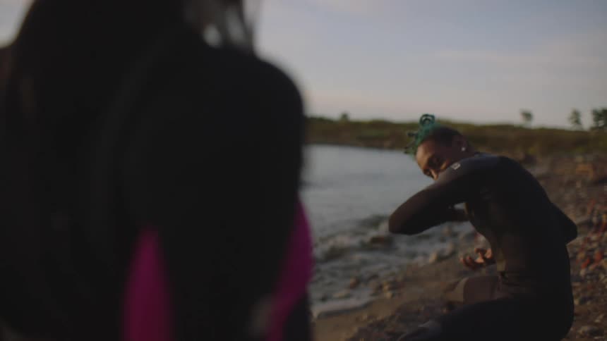 A man and woman on a beach are acting out an anime scene at dusk