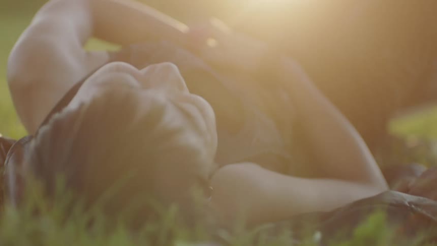 A boyfriend and girlfriend laying outdoors together