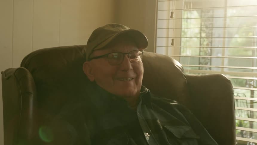 A man laughs while watching television at home
