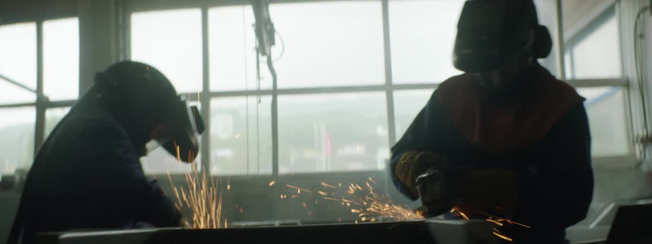 Two co workers grinding on pieces of metal