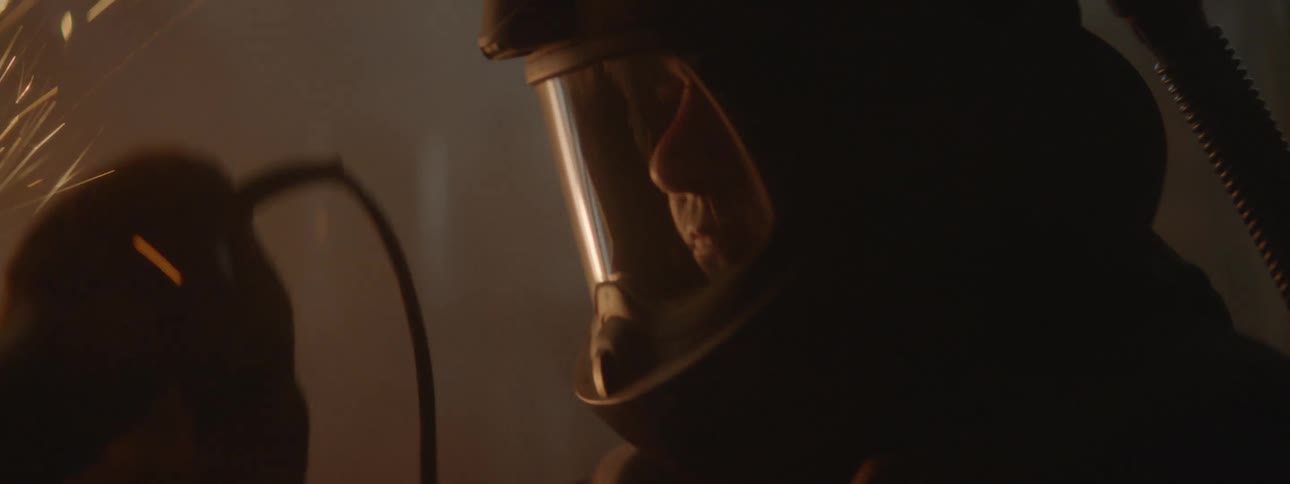 A man in safety gear uses a tool to cut metal