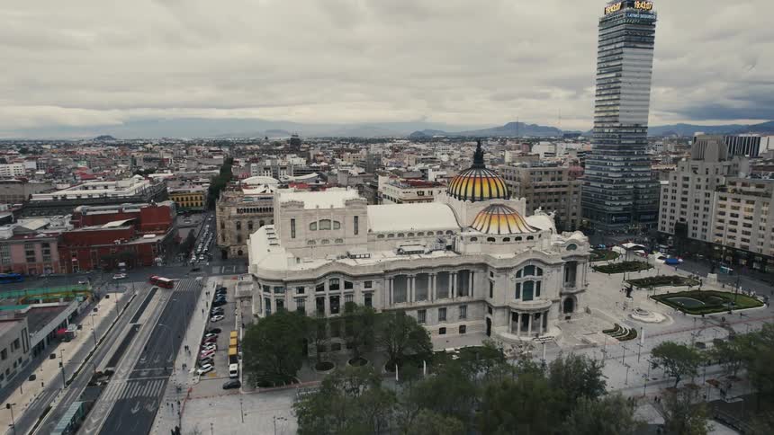 Building with colorful domes and statue stand near plaza and park in center of city stretching to horizon mountains
