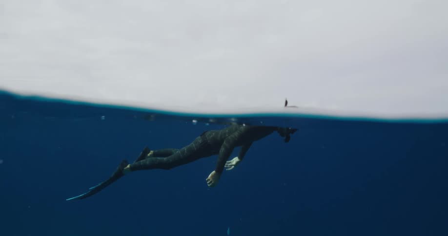 A scuba diver is floating underwater with a snorkel sticking out above the water