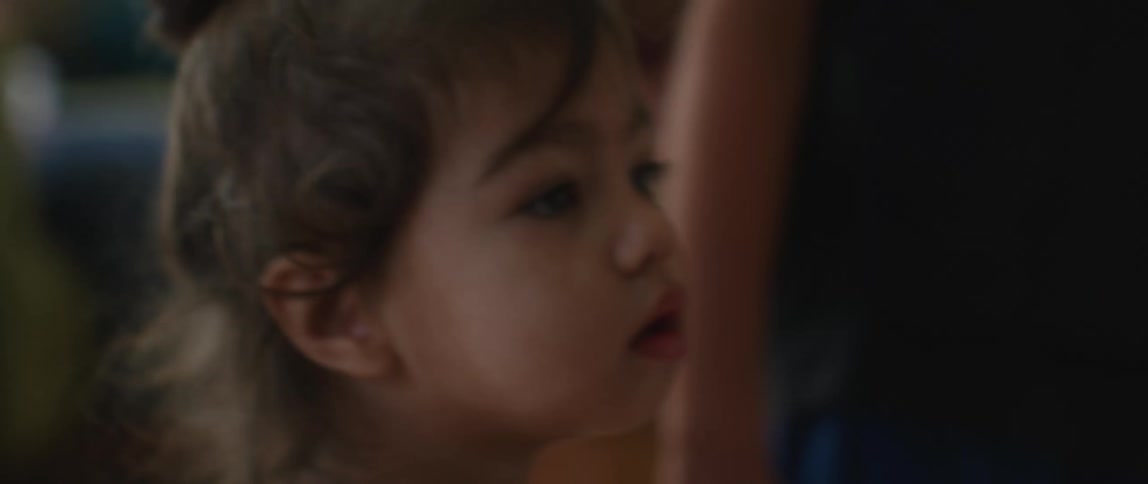 A toddler watches as her parents hang a turkey made of construction paper on the wall