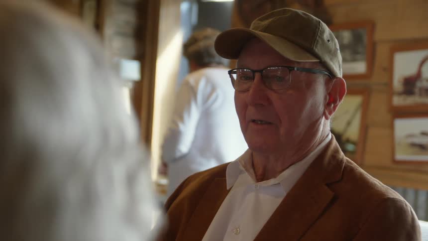 A man nods while chatting with a woman in a restaurant