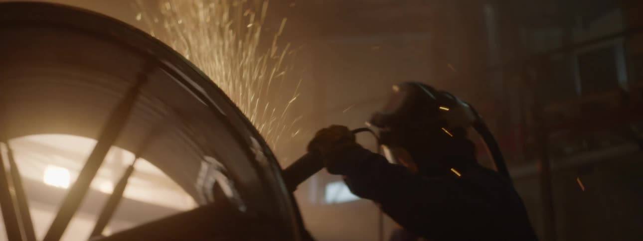 A person in protective gear cuts a round cylinder