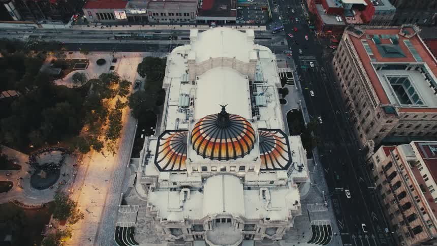 Vehicles drive past a large white building with colorful ornate domes