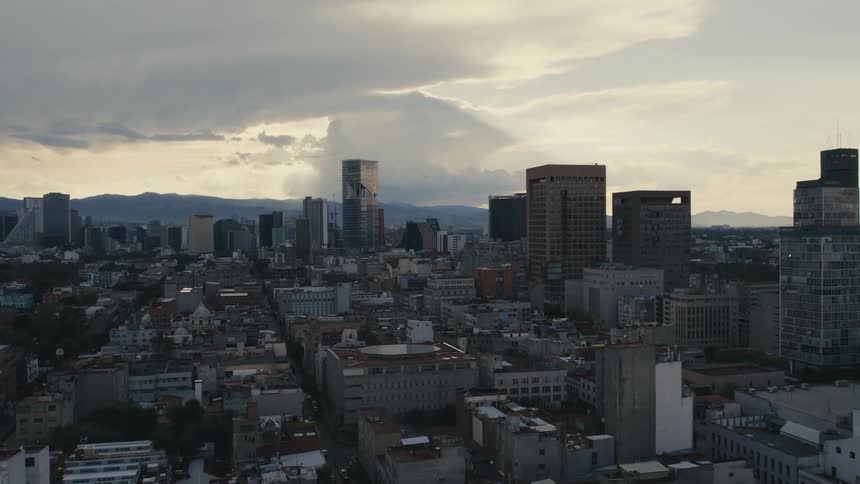 Big city with tall buildings and mountains on the horizon under a cloudy sky