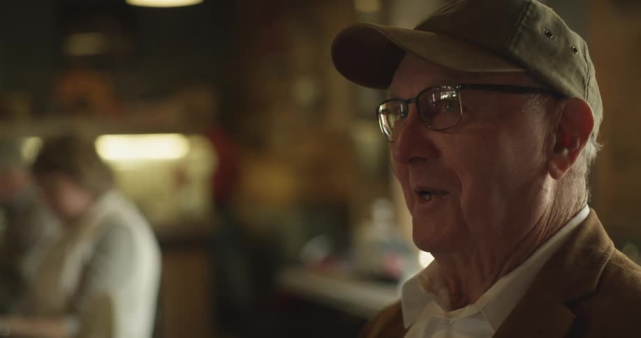 Elderly senior citizen sitting on at a restaurant table talking to friends