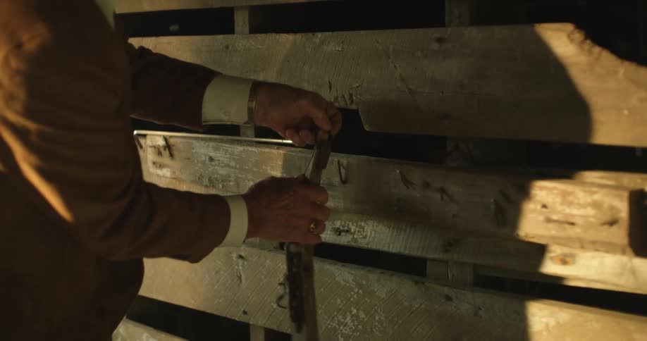 A man lifts a tool and hangs it on the wall